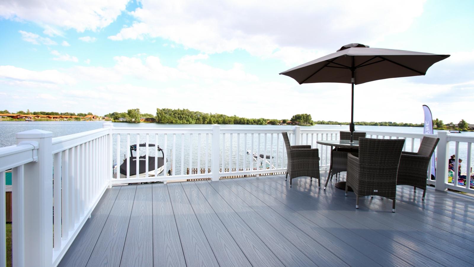 Grey Liniar decking with white balustrade fencing, table and chairs with parasol