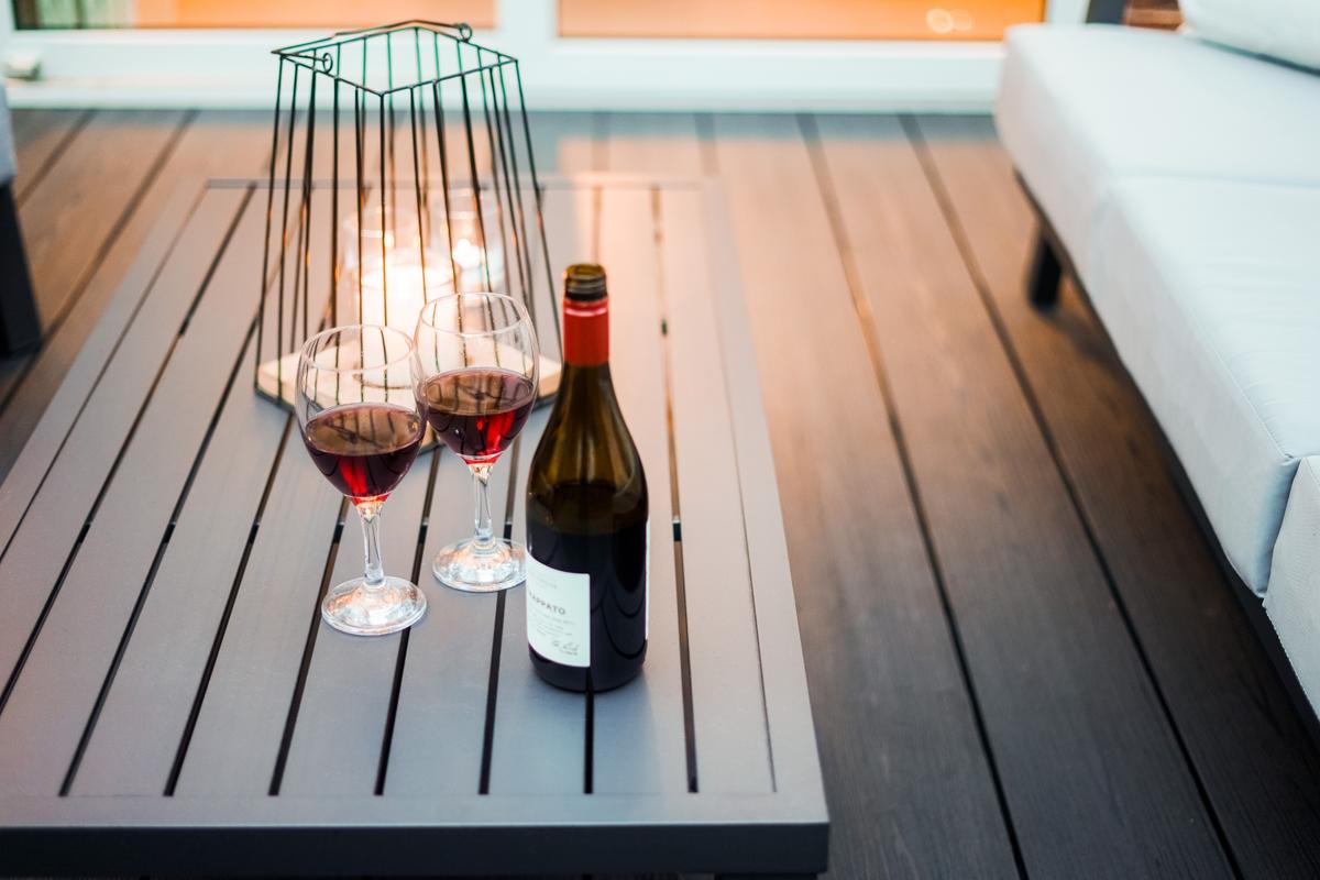 A bottle of red wine next to two glasses on a Liniar SwitchBoard Ultra PVCu decking area