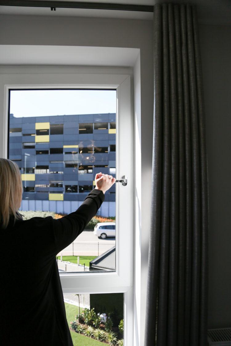 woman closing a white EnergyPlus90 window by Liniar 