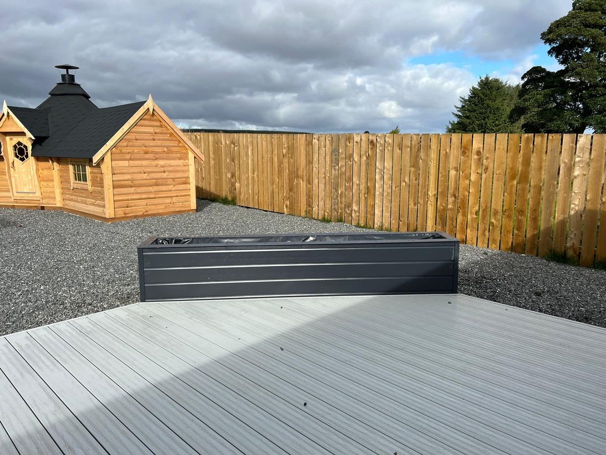 Liniar SwitchBoard decking featuring a planter made with Anthracite grey shiplap cladding, with a timber garden room in the background