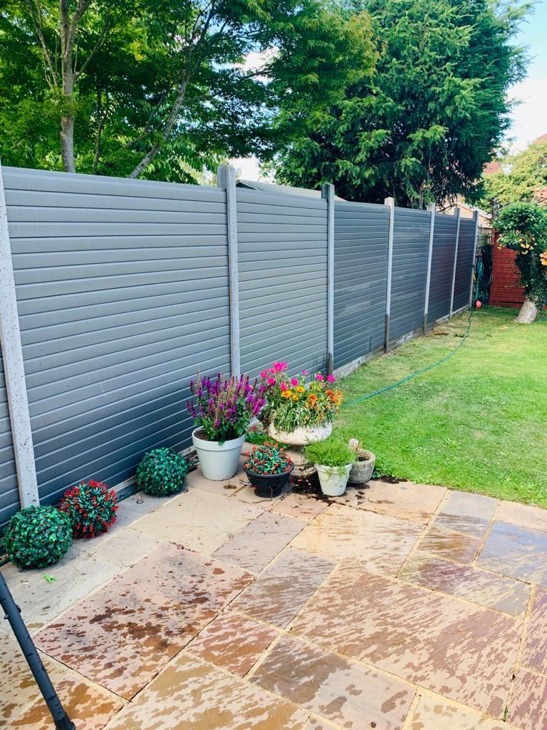 Grey composite fencing in a garden with planters
