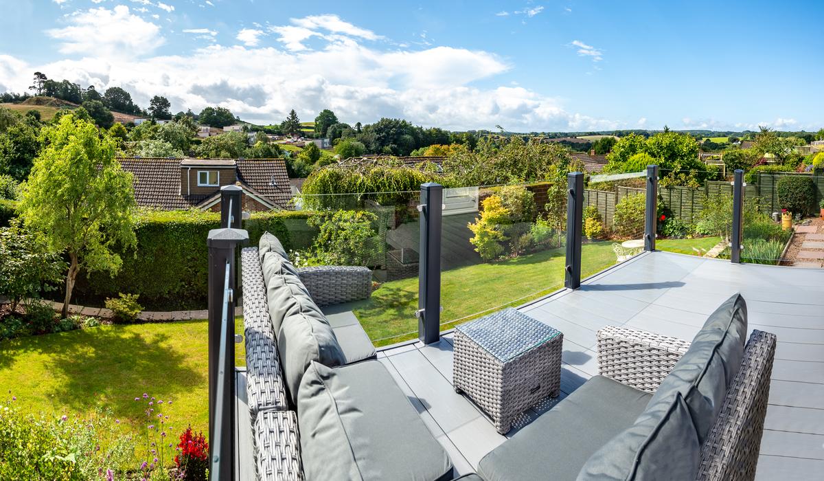 Grey Liniar decking with glass balustrades in garden 